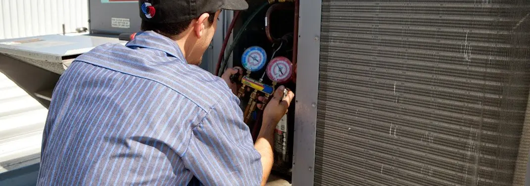 HVAC technician servicing a condenser unit in Valley Center